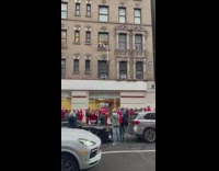 Two guys give drink on rope to a woman in santa outfit from window