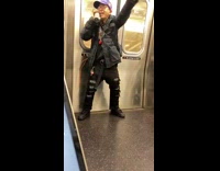 Guy holding speaker on subway train playing music and dancing