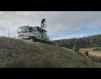Guy jumps blue bicycle truck grass hill