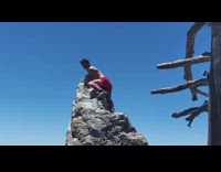 Three men picture friend top of rock red shorts