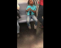 Boy blue shirt plays with black rat toy on subway train