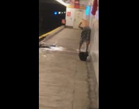 Shirtless guy in gray plaid shorts takes a shower at subway station