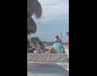 White drone flies over people at beach 