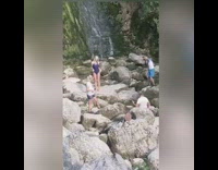 Purple bathing suit girl waterfall grey rocks 