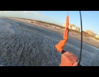 Guy kitesurfing over ocean falls in water 