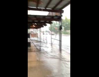 Man Holds on Scaffold to Cross Flooded Sidewalk