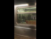 Guy blue tank top carries red white striped long stick pole onto subway train