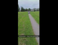 Guy rides small white toy car grass