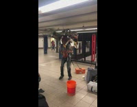 Collab Subway Creatures - Man sings Rudolph the Rednose Reindeer, plays guitar, other instruments on his back