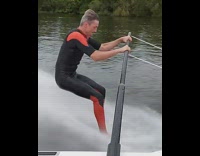 Black orange wetsuit guy barefoot water ski 