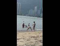 Guy black pink shorts kick beach water