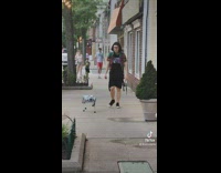 Guy walking on sidewalk with robotic dog 
