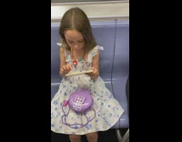 Little girl sitting down on subway next to guy rolling marijuana joint