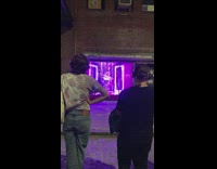 2 People watch pole dance at storefront 