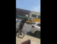 Guy balances soccer ball head red bicycle 
