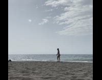 Bikini girl jump pose beach guy sits 