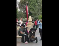 Woman with Minnie mouse ears takes picture in front of Disneyland castle
