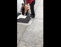 Woman lays shirt flat on ground and takes picture on sidewalk