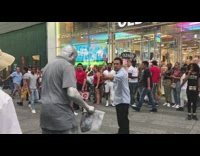 Guy kicks silver mans bucket of money on sidewalk and get in a fight, spiderman comes in and breaks up the fight