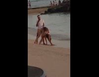 Two women bend over in front of man at the beach