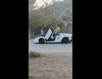 Man in yellow outfit on top of white sports car