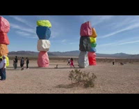 Woman in pink outfit poses on the stacked colored rocks