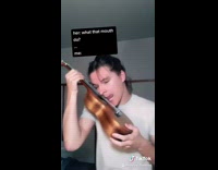 Guy uses tongue to strum ukulele instrument 