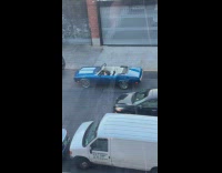 Man vapes on blue convertible car on street