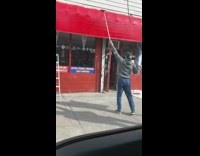 Man paints his awning red with a paint roller