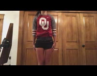 Girl in red OU shirt makes a cheerleading tryout video, kicks leg up and falls backwards onto ground