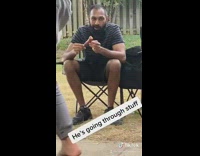 Guy sits chair eats sausage stares backyard