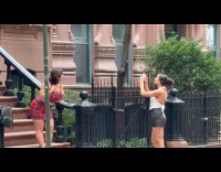 Woman red checkered dress poses on sidewalk