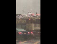 Hurricane rain pours onto New york bus tourists on open double decker bus with ponchos