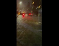 Pedestrians walk through flood water up to their knees 