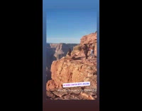 woman sits edge canyon black jacket