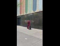 Guy in spiderman outfit and red suit karaoking on sidewalk