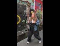 Woman in jean jacket with camera mounted on her body on the alley