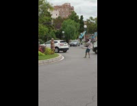 Old woman in brown outfit poses on the side of the street