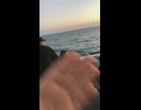 Woman waves at the ocean on fishing dock