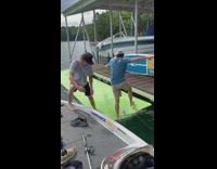Guy jumps onto green floating strip gets back on boat 