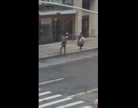 Woman in black outfit and blue boots poses on the sidewalk
