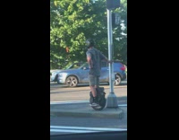 Boy waits for light to turn green on electric unicycle 