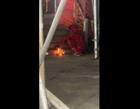 Collab WINY - Man in red onesie makes campfire on sidewalk