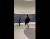 Woman in black dress poses beside artwork