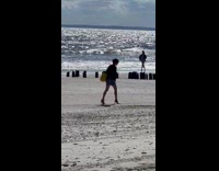 Man walking in heals on sand at beach