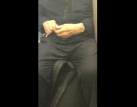 Old man with backpack between legs cuts fingernails on subway train