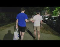 Two guys walking both supporting one frenchie with one hand each