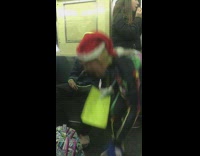 Donald Trump mask in Santa Claus hat and rainbow skeleton suit holds yellow sign