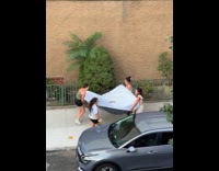 Four women carries bed mattress on street