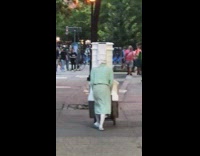 Person wearing blue dress pushes cart with prop